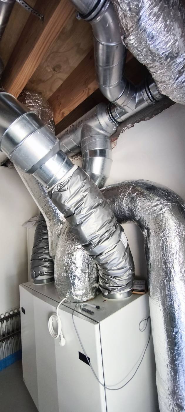 Vue rapprochée d'un groupe de ventilation double flux sous charpente
